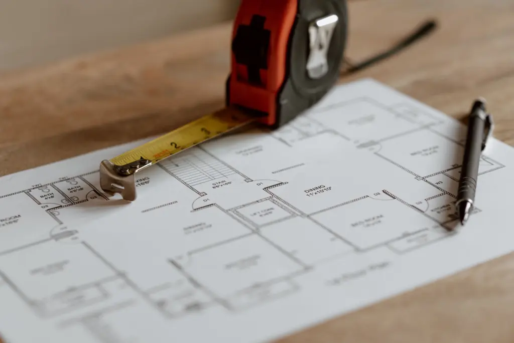 Mètre ruban et stylo posés sur le plan d’un appartement
